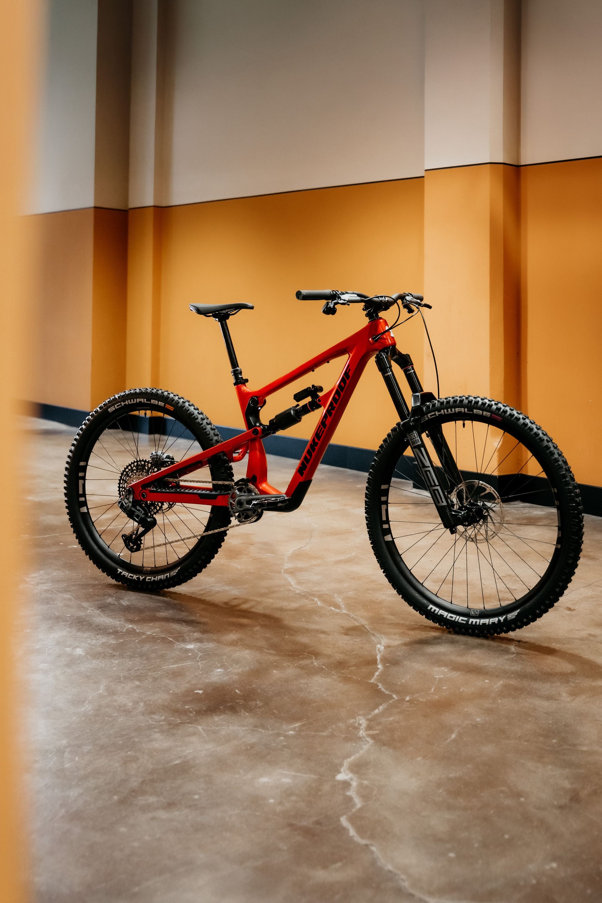 Red mountain bike on a concrete floor with a yellow wall in the background
