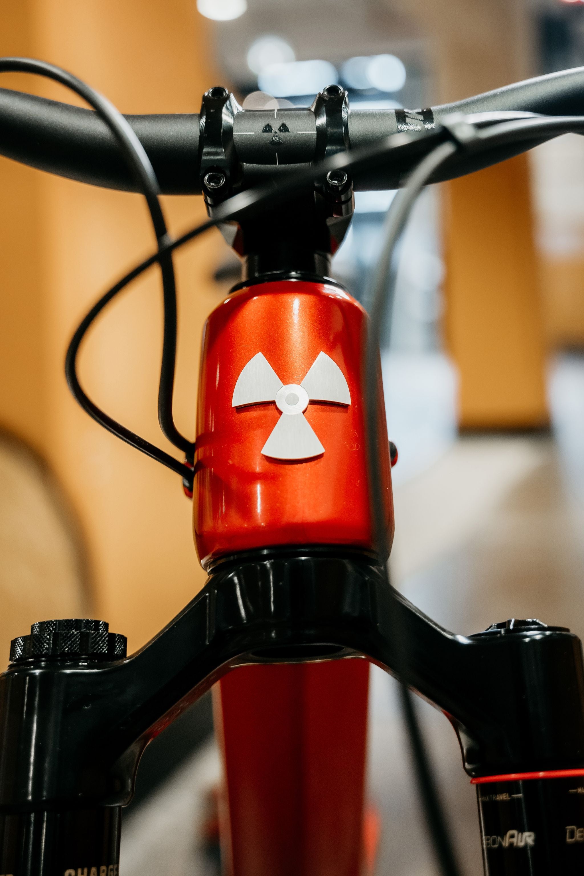 Close-up of a bicycle handlebar with a red stem featuring a white logo.