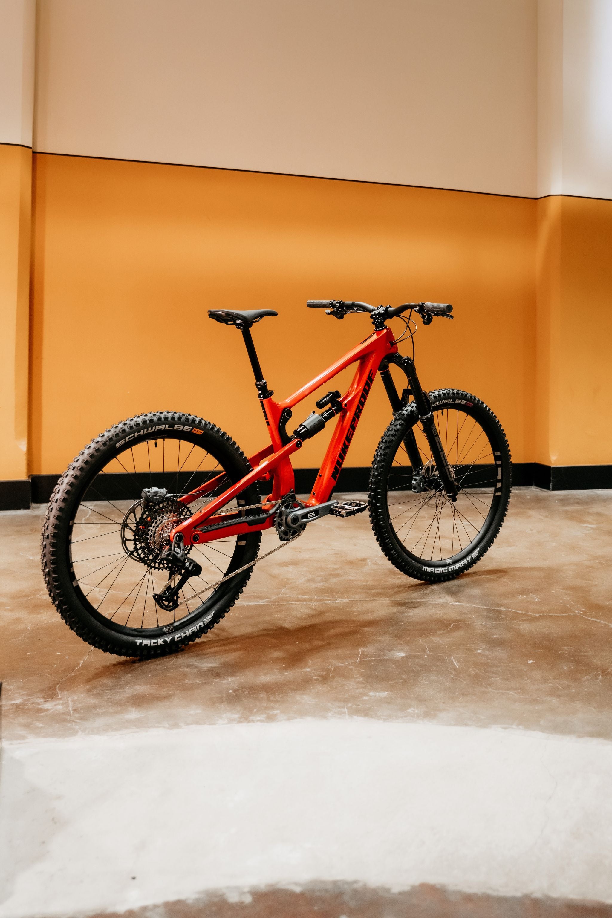 Red mountain bike on a concrete floor with an orange wall background