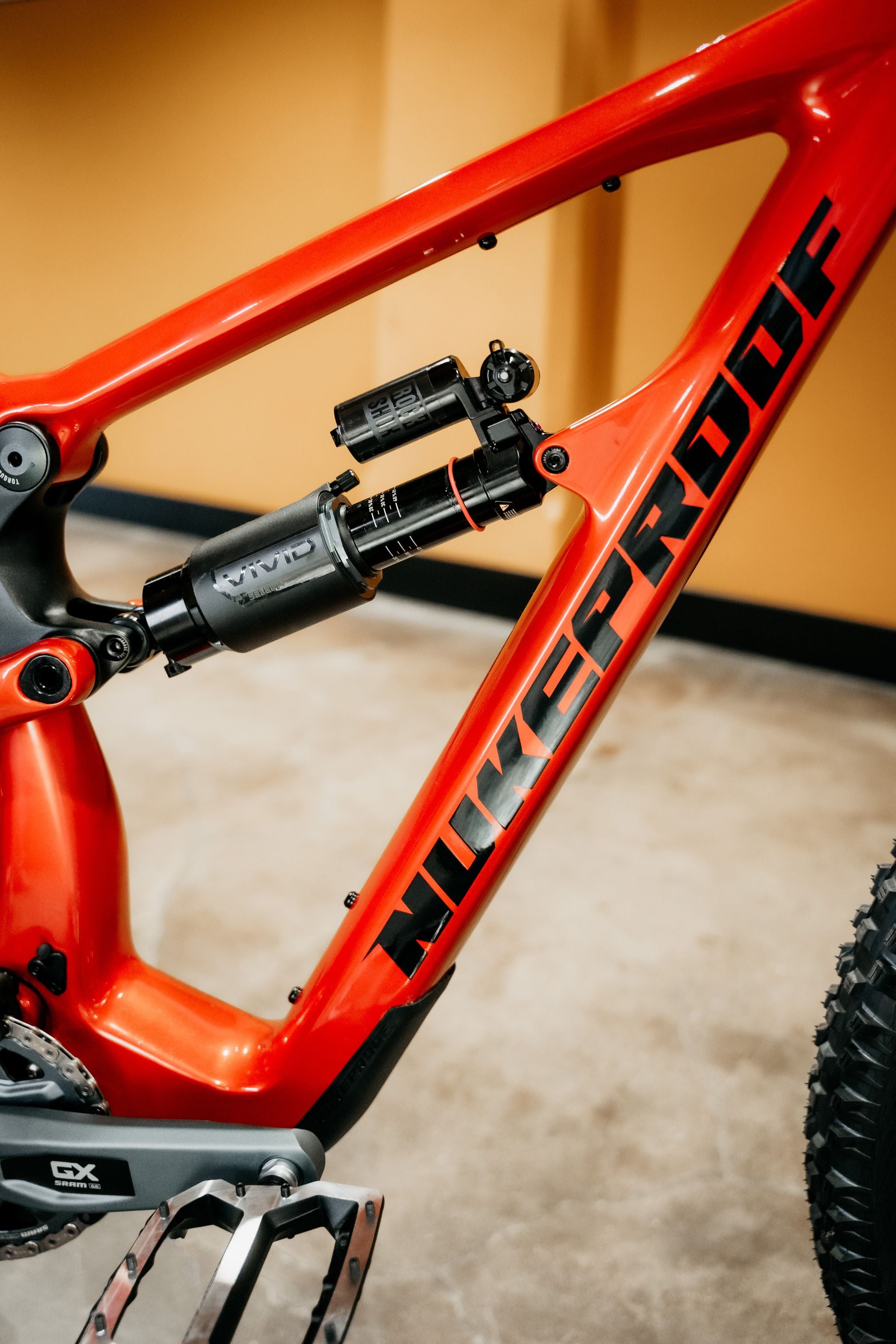Close-up of a red mountain bike frame with 'nukeproof' branding on a blurred background