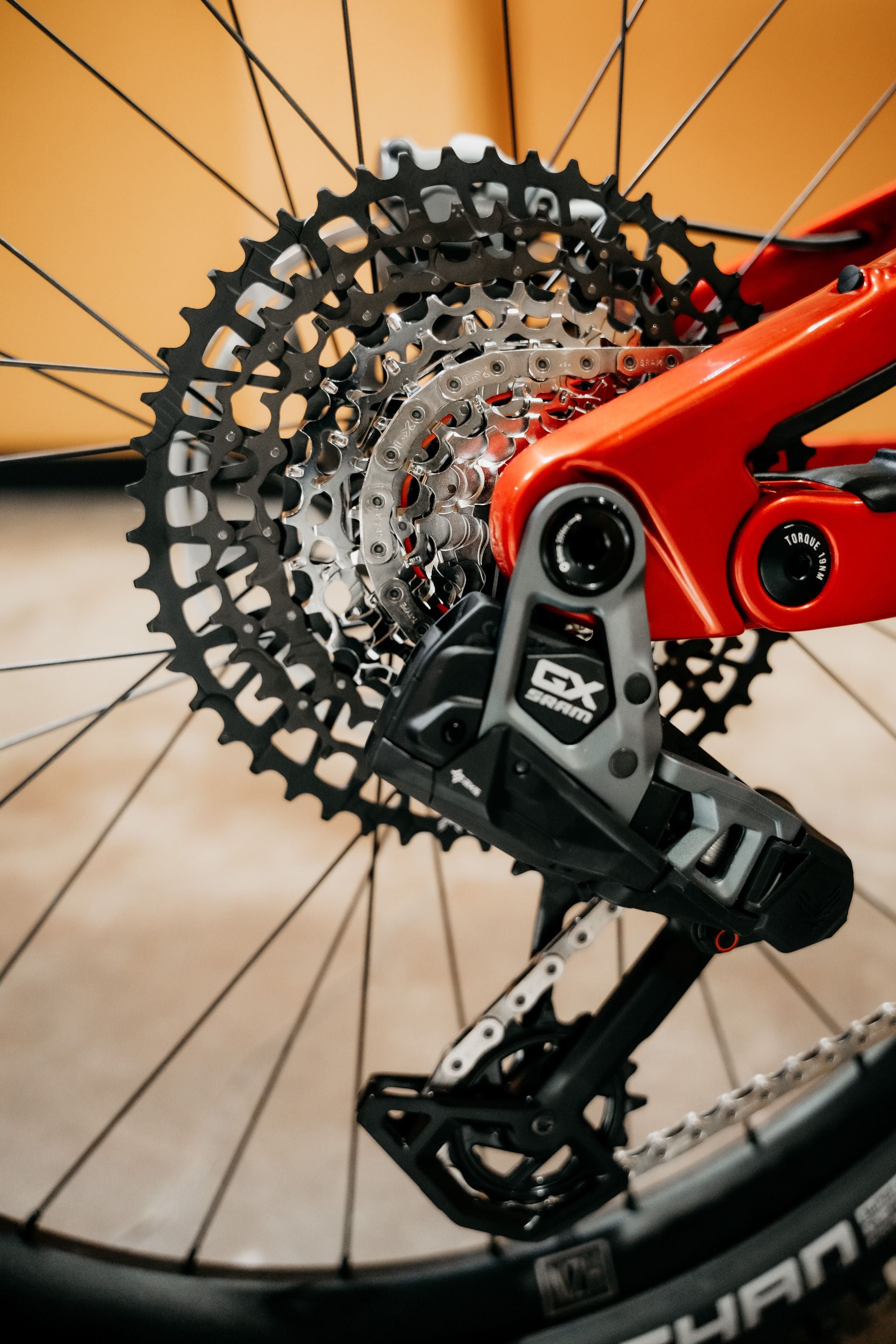 Close-up of a bicycle gear system with a red derailleur on a blurred background