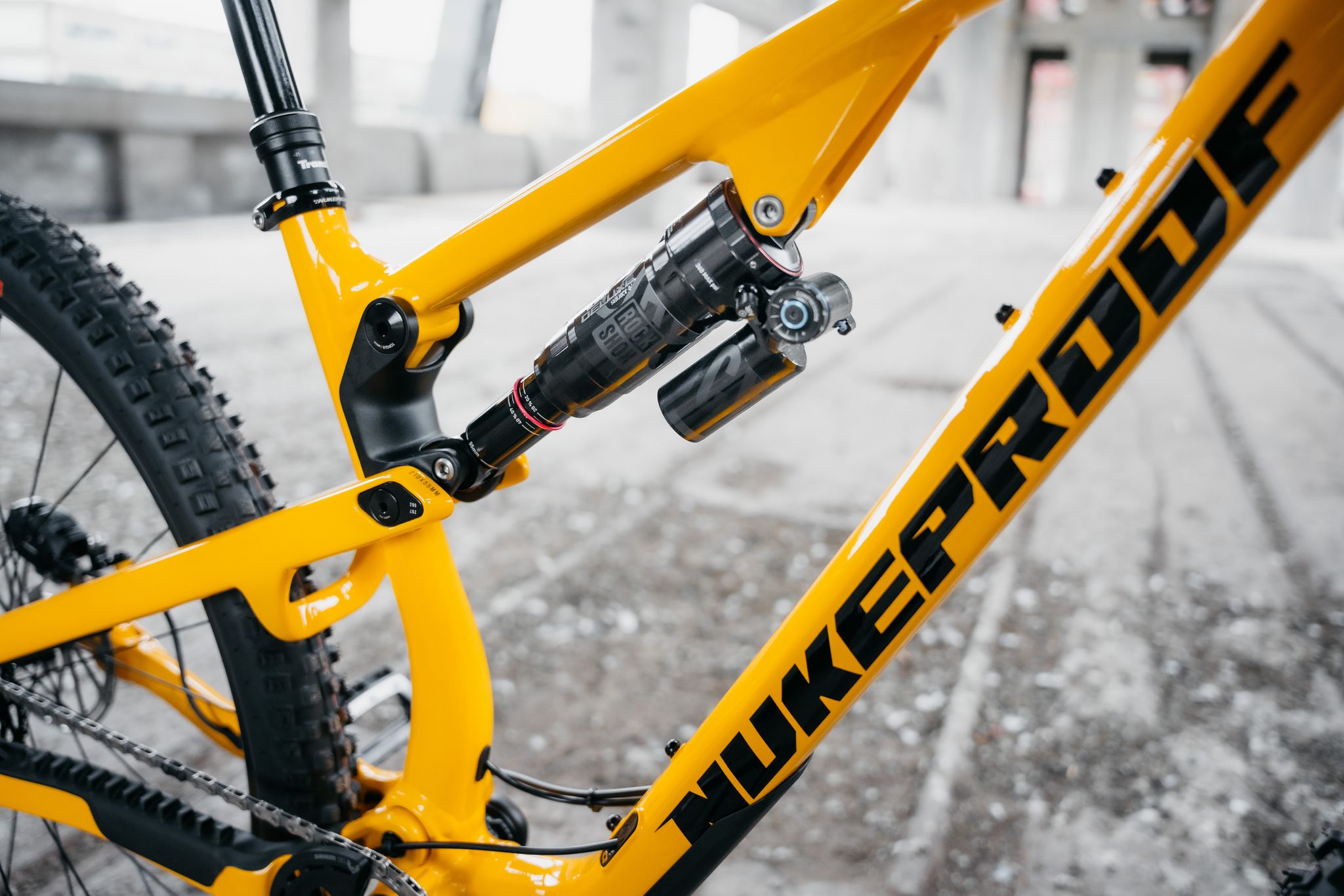 Close-up of a yellow bicycle frame with 'NUKEPRO' branding on a snowy background.